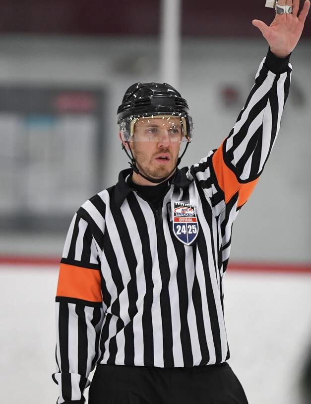 Colorado ice hockey official raising an arm to signal